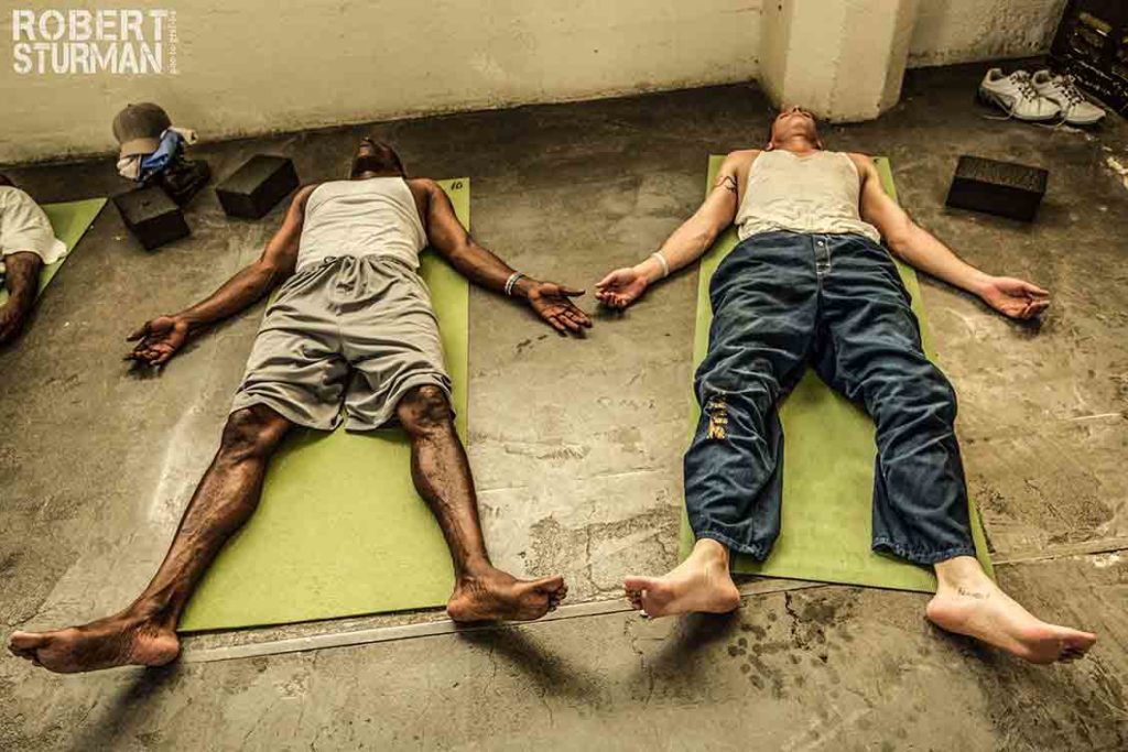 Picture of two incarcerated people, one White and one Black, in corpse pose.